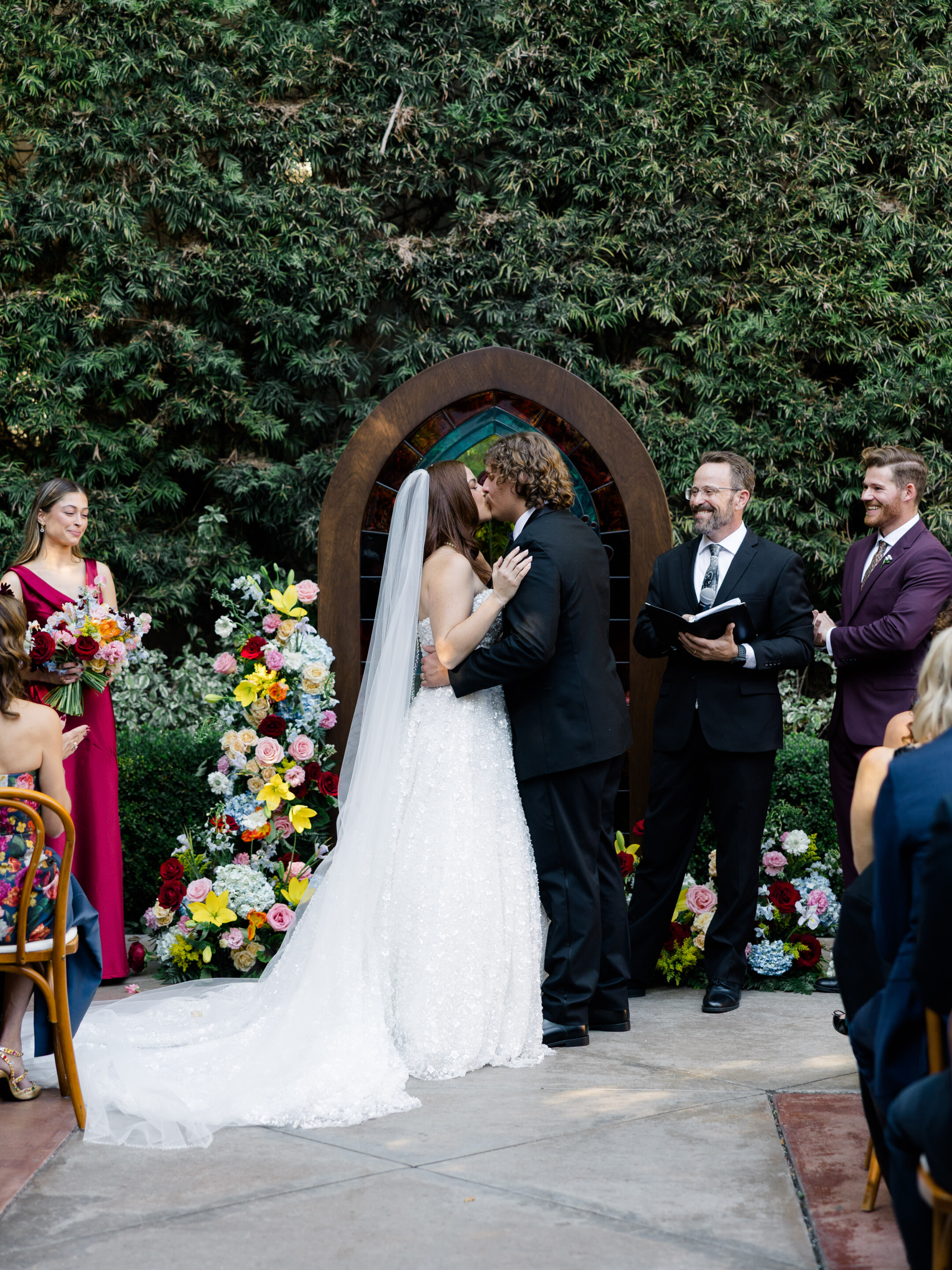 bride and groom kissing in front of colorful flowers at franciscan gardens san juan capistrano california